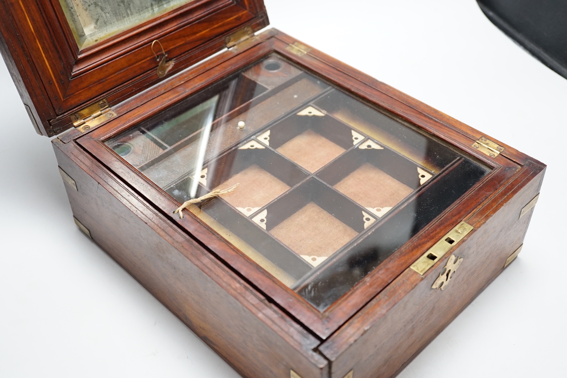 An Anglo-Indian wooden brass bound sewing box, with fitted interior and removable sections, hinged bevelled mirror, internal glass lid, etc. lock marked Birmingham, 26cm x 31cm x 14cm